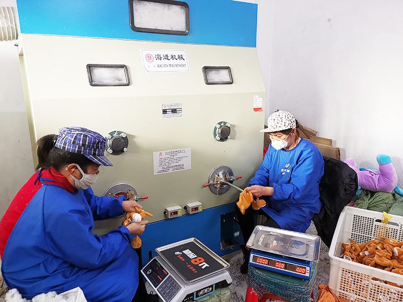 Workers at stuffing machines filling plush toys